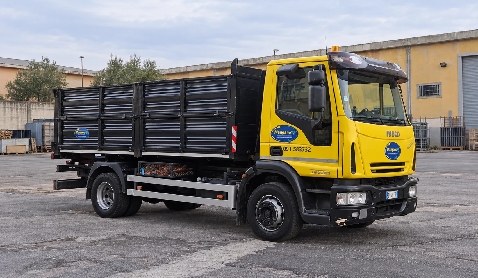Camion Iveco Mangano con cabina gialla e cassone nero per smaltimento rifiuti